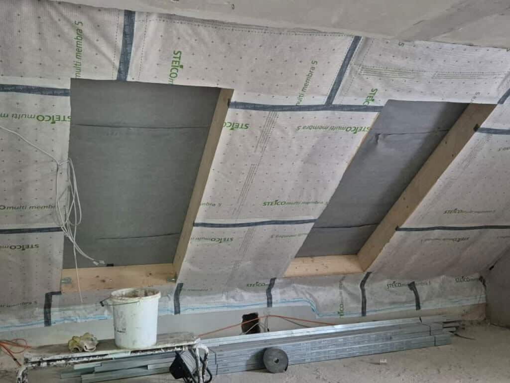 Integration von Dachflächenfenstern im Dachgeschoss. Vorbereitete Dachflächenfenster mit Dachdämmung und Luftdichtheitsebene im Dachgeschoss während einer energetischen Sanierung.