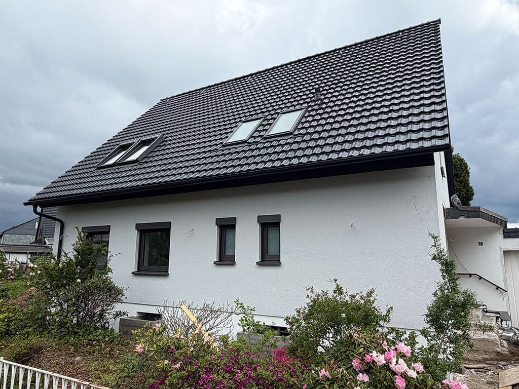 Fertiggestellte Dachsanierung und modernisierte Gebäudehülle. Außenansicht eines kernsanierten Wohngebäudes in Langenfeld mit neuer Dacheindeckung, Dachfenstern und modernisierter Fassade.