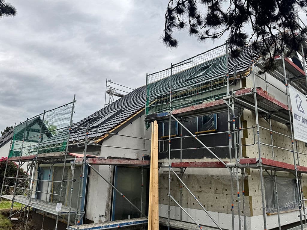 Neue Dacheindeckung und Fassadendämmung. Wohngebäude während der Sanierung mit neuer Dacheindeckung und Fassadendämmung zur energetischen Modernisierung der Gebäudehülle.