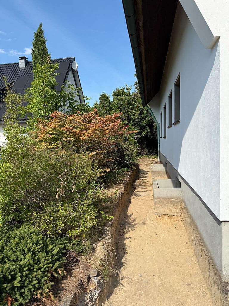 Freilegung der Kellerwand zur Vorbereitung der Abdichtungs- und Sanierungsarbeiten. Freilegung des Gebäudesockels zur Vorbereitung der Kellerabdichtung im Zuge der Kernsanierung eines Wohngebäudes in Langenfeld.