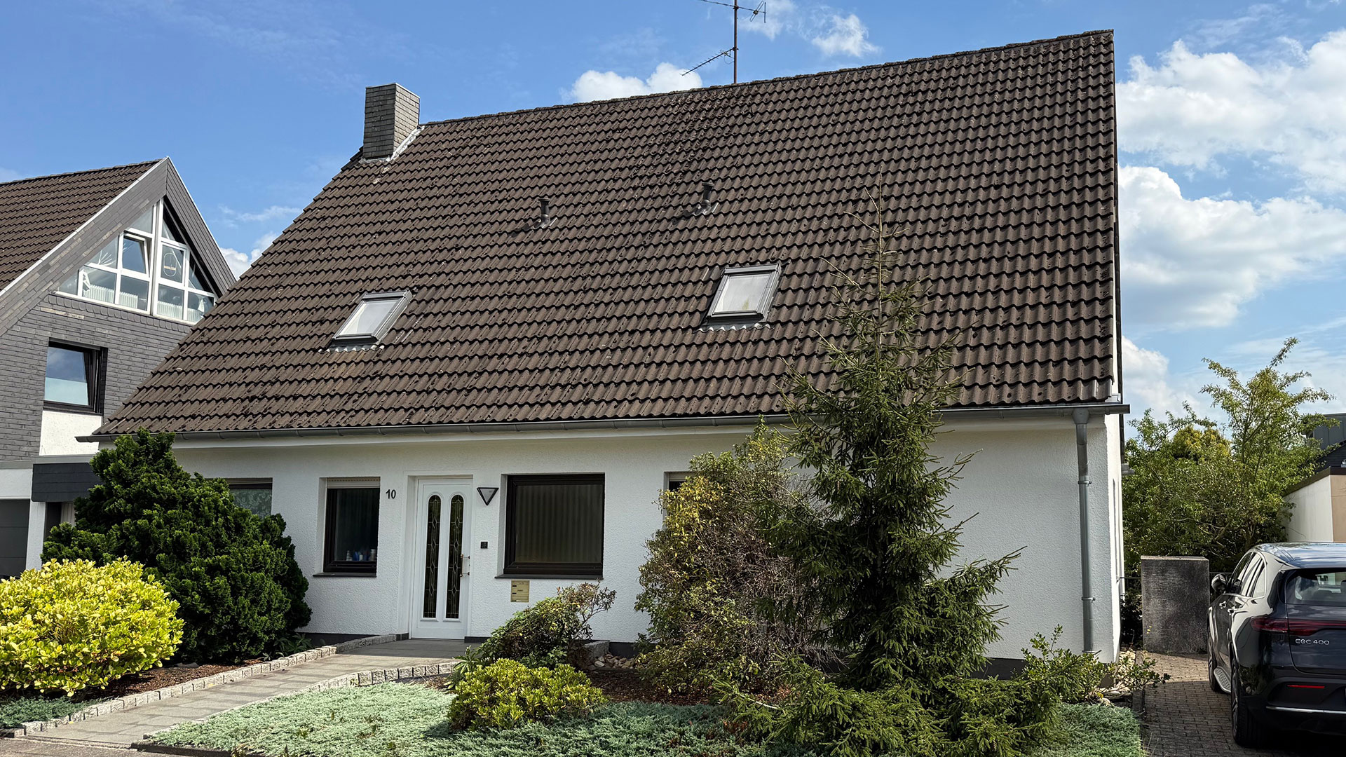 Außenansicht eines Zweifamilienhauses in Langenfeld vor Beginn der Kernsanierung mit bestehender Fassadengestaltung, Dachfläche und angelegtem Vorgarten.