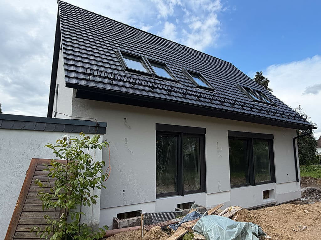 kernsanierung-langenfeld-fertiggestellte-dachsanierung-neue-fenster-s03-cardbau Außenansicht eines kernsanierten Wohngebäudes in Langenfeld mit neuer Dacheindeckung, Dachfenstern und modernen Fensterelementen.