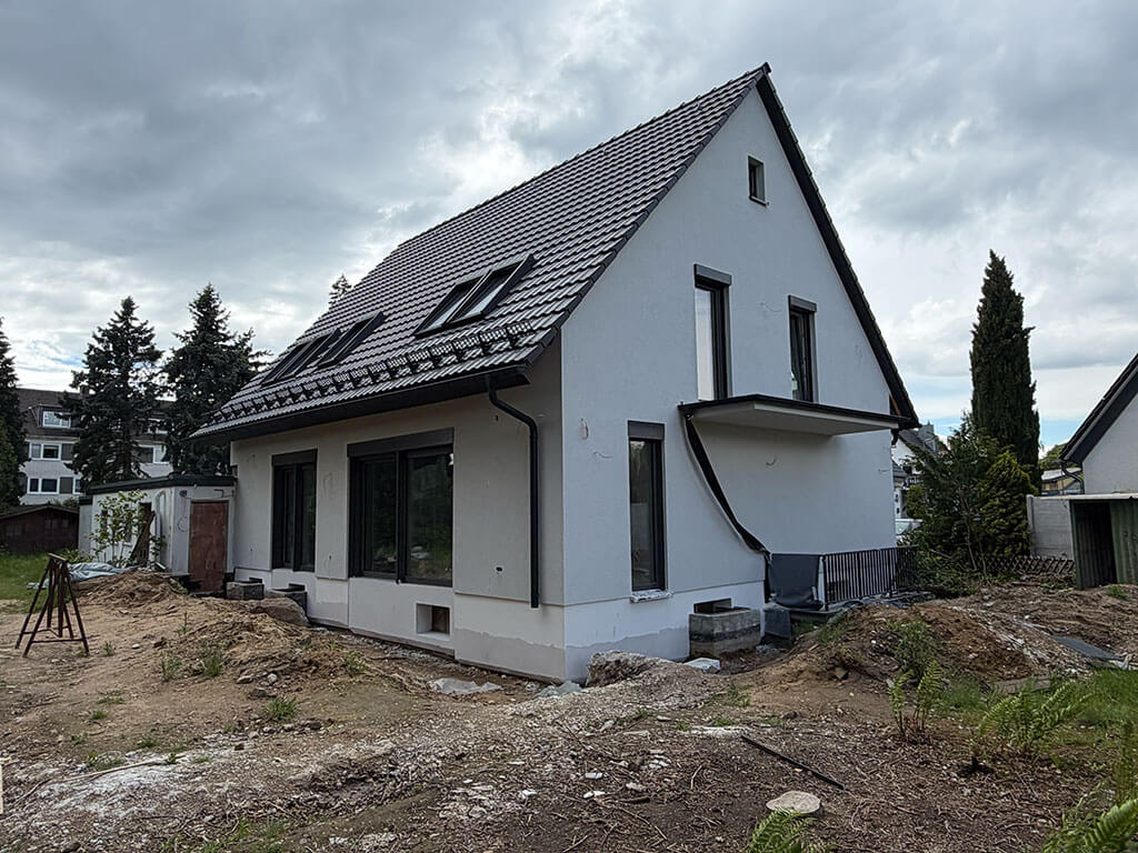Modernisierte Gebäudehülle nach umfassender Kernsanierung. Außenansicht eines kernsanierten Einfamilienhauses in Langenfeld mit neuer Dacheindeckung, Dachfenstern und modernisierten Fensterelementen.