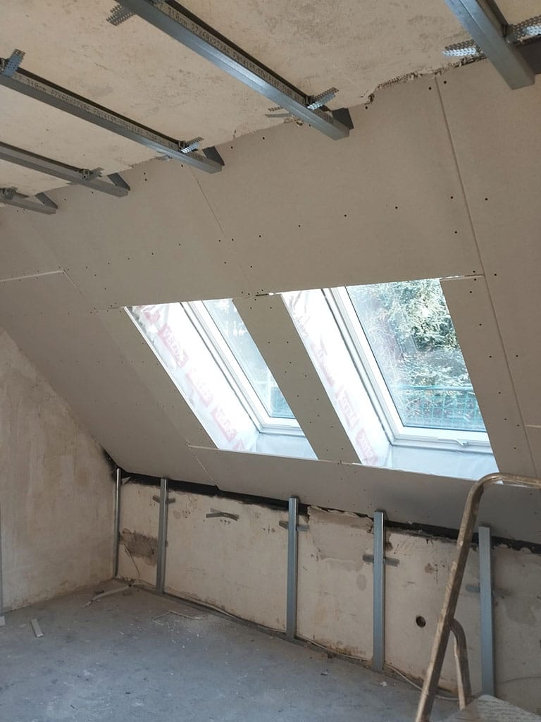 Verkleidung der Dachschrägen und Dachfenster im Rahmen des Innenausbaus. Trockenbauarbeiten mit Verkleidung neu eingebauter Dachfenster im Zuge der Kernsanierung eines Wohngebäudes in Langenfeld.