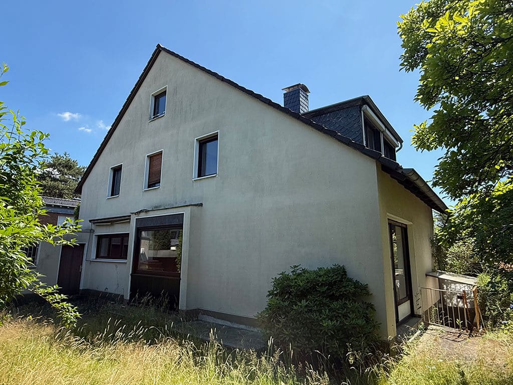 Seitenansicht des Bestandsgebäudes vor der Sanierung. Seitenansicht eines Wohngebäudes in Köln-Rath vor der Kernsanierung mit bestehender Fassade, Dachgaube und Fenstern im Bestandszustand.