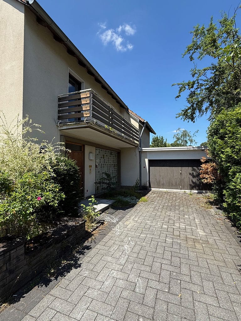 Eingangsbereich vor der Kernsanierung. Eingangsbereich mit Balkon und Garage eines Wohngebäudes in Köln-Rath vor Beginn der Kernsanierung im Bestandsgebäude.